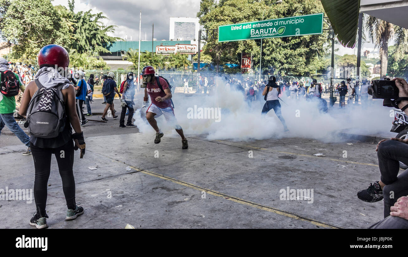 I dimostranti prendere la copertura dalla polizia cannone ad acqua durante una marcia verso l'ufficio del Mediatore in segno di protesta del Presidente Nicolas Maduro in Caraca Foto Stock