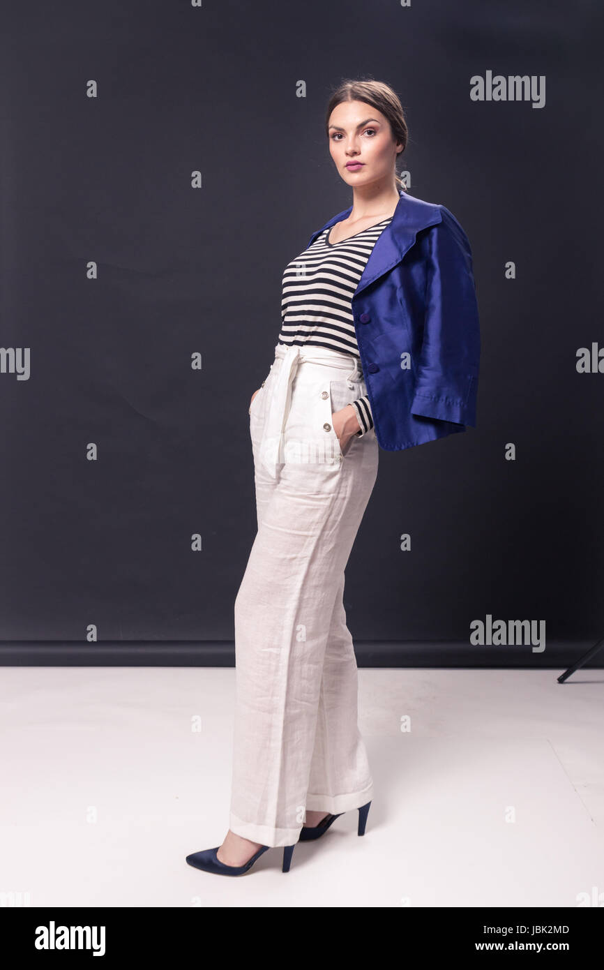 Una giovane donna caucasica 20s, 20-29 anni, moda modello ponendo permanente, studio, sfondo bianco camicia alla moda, orizzontale camicia striscia, pant Foto Stock