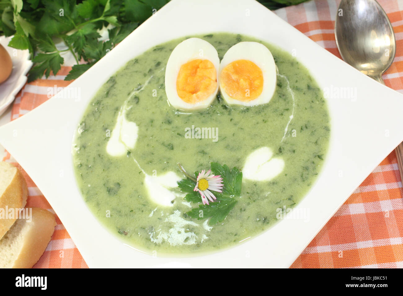 Grüne Kräutersuppe mit Eiern, Sahneklecks und Gänseblümchen Foto Stock