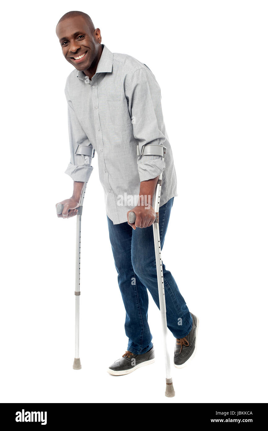 Uomo sorridente con le stampelle cercando di camminare Foto Stock