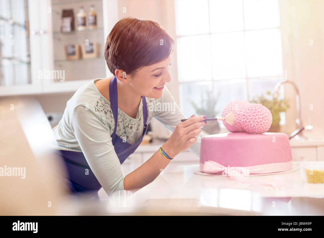 Femmina finitura catering rosa torta nuziale in cucina Foto Stock