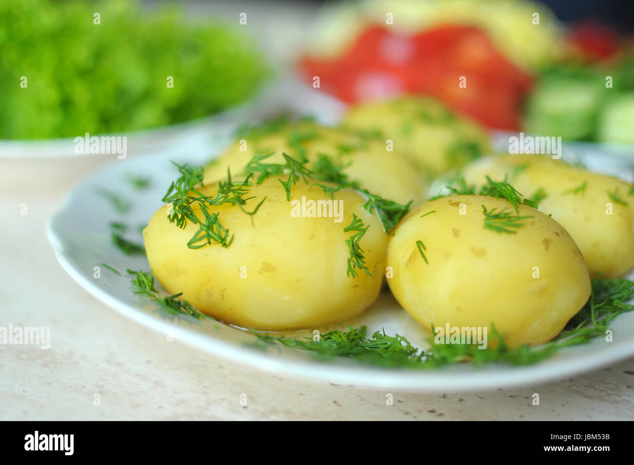 Freschi ortaggi e patate novelle bollite sulle piastre sul tavolo di legno. Close up, il fuoco selettivo. Foto Stock