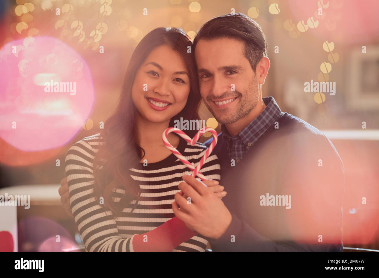 Ritratto sorridente giovane azienda cuore-forma candy canes Foto Stock