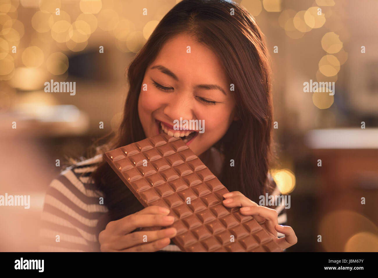 Donna con sweet tooth craving mordere in grandi barra di cioccolato Foto Stock