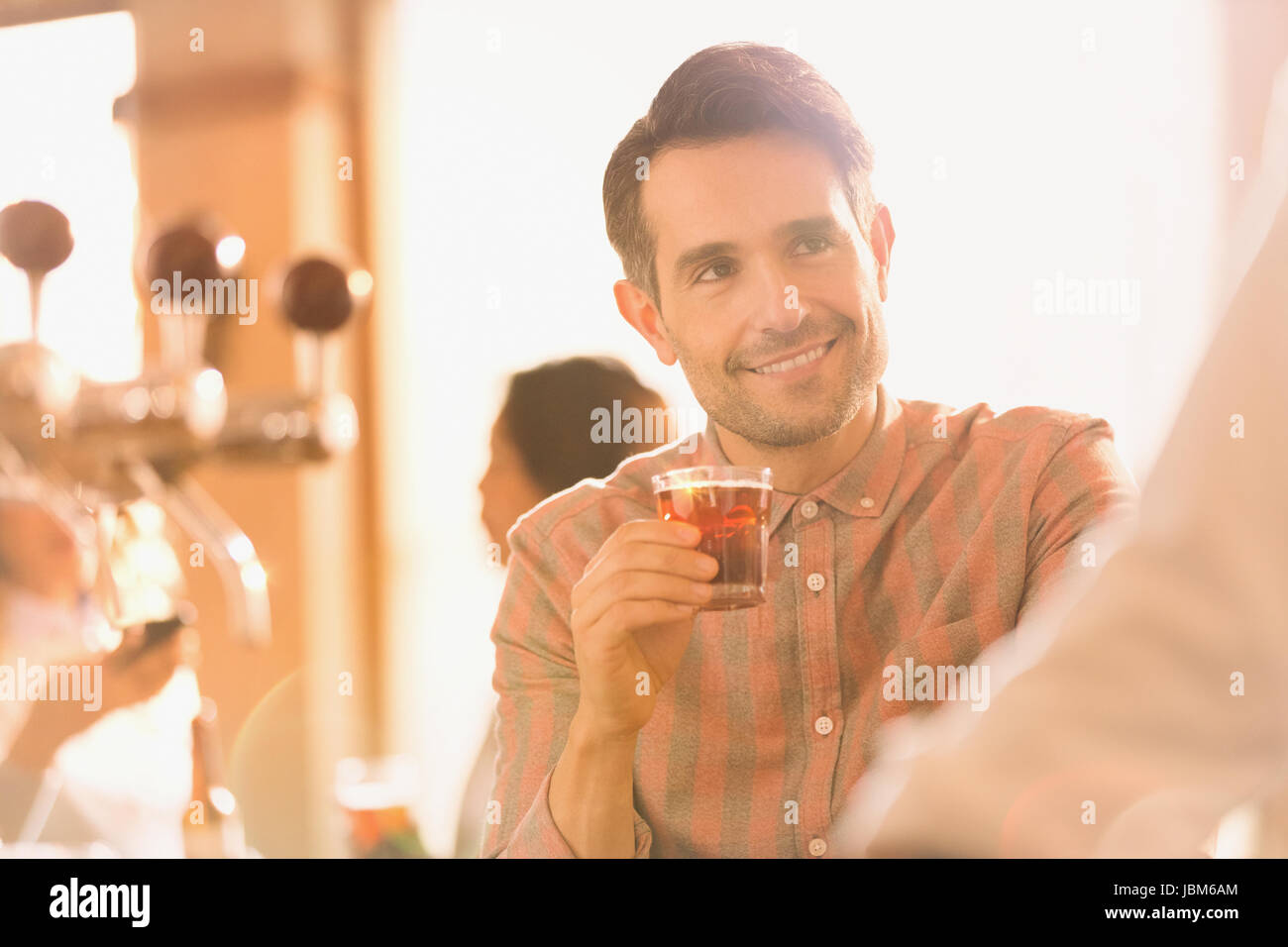 Uomo sorridente bevendo cocktail al bar Foto Stock