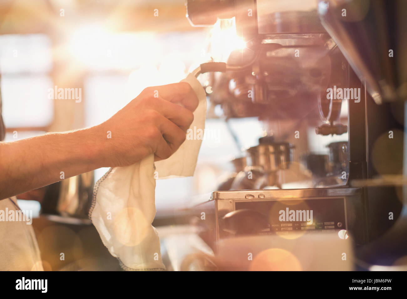 Close up barista strofinando macchina espresso frother latte con rag in cafe Foto Stock