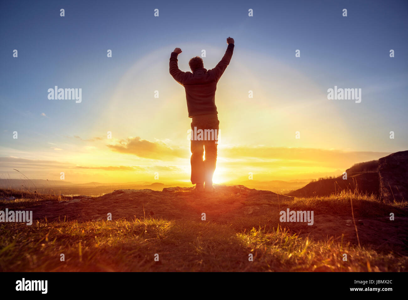 Uomo felice celebrando conquistando il successo o di adorazione e di lode nei confronti di tramonto Foto Stock