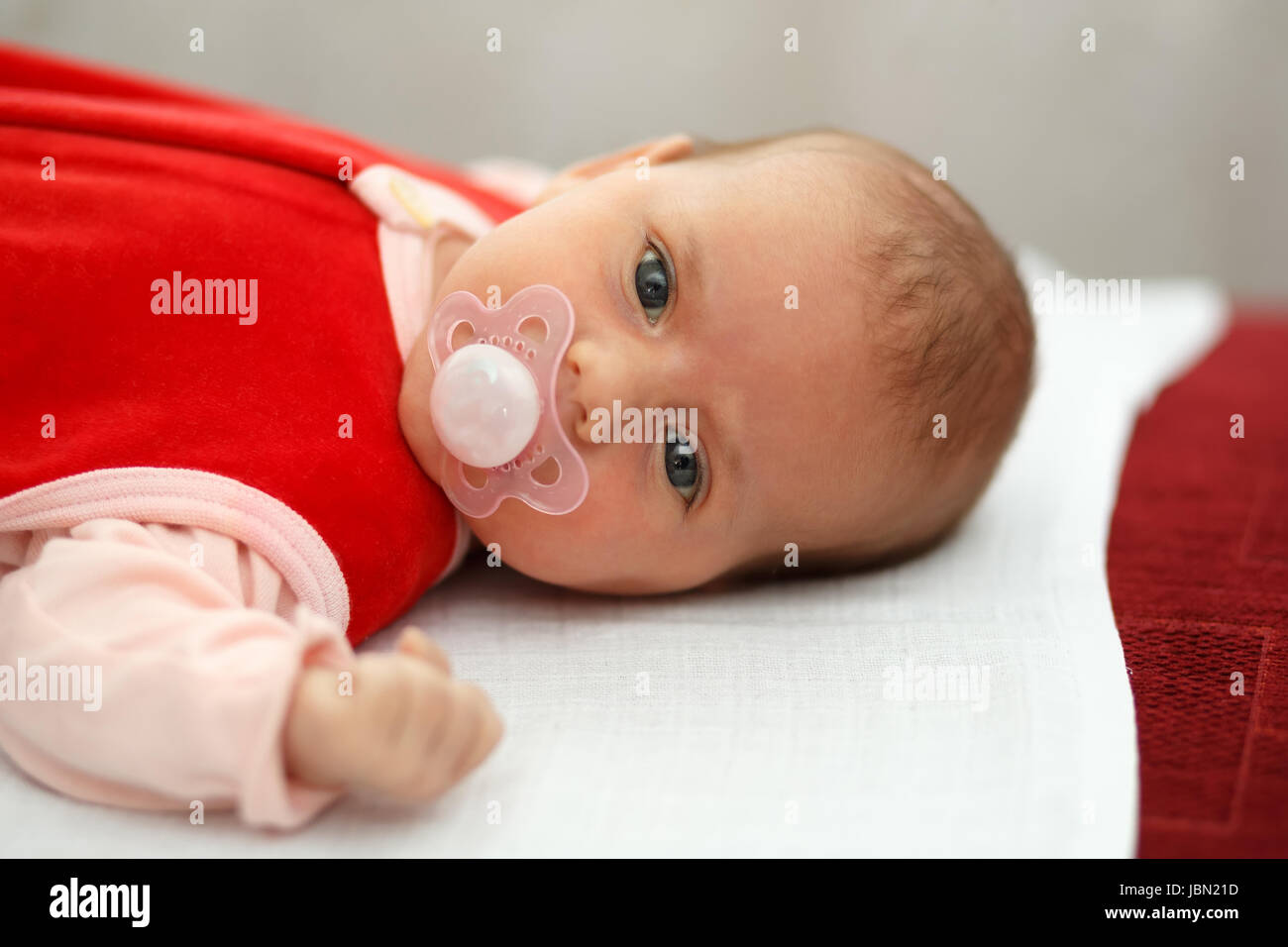 Neonato, giacenti da più di un mese il bambino in abito rosso con succhietto Foto Stock