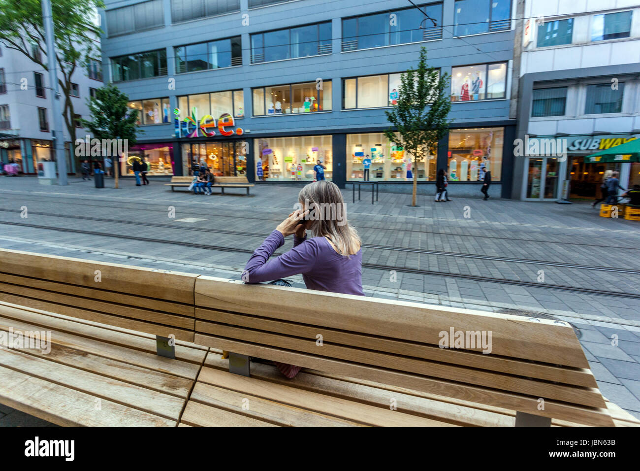 Donna a panchina, vista posteriore sola Konigstrasse. Kassel, Assia, Germania Foto Stock