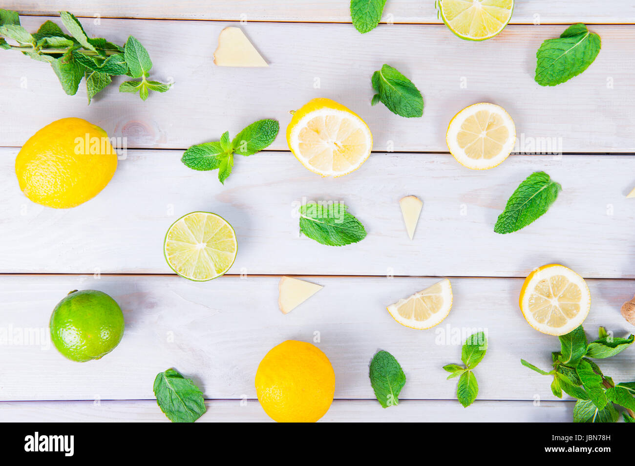 Pattern colorati di menta, calce, limone,fettine di zenzero. . Cedri e limoni tagliati a fette e intera con foglie. Bianco su sfondo di legno. Vista dall'alto. Foto Stock