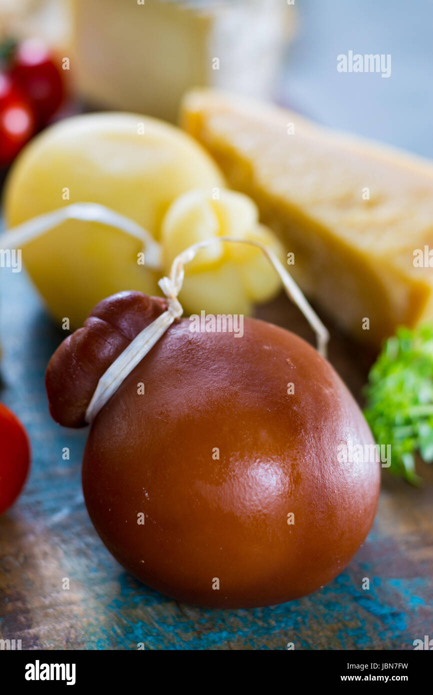 Tradizionale formaggio duro italiano Provolone Caciocavallo affumicato e bianco su sfondo di legno Foto Stock
