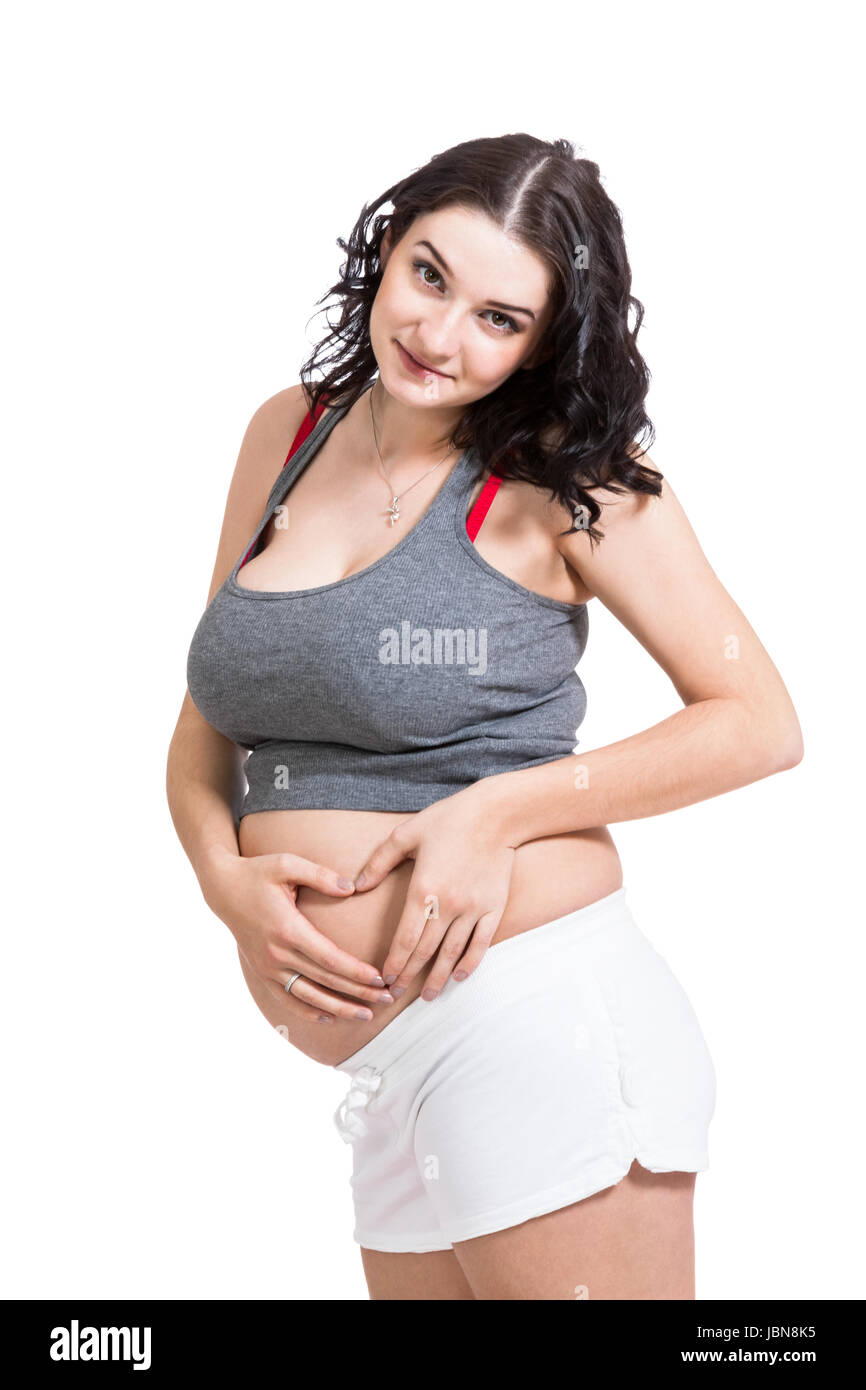 Junge schwangere Frau formt mit Ihren Händen ein Herz vor Ihrem Babybauch isoliert vor weißem Hintergrund Foto Stock