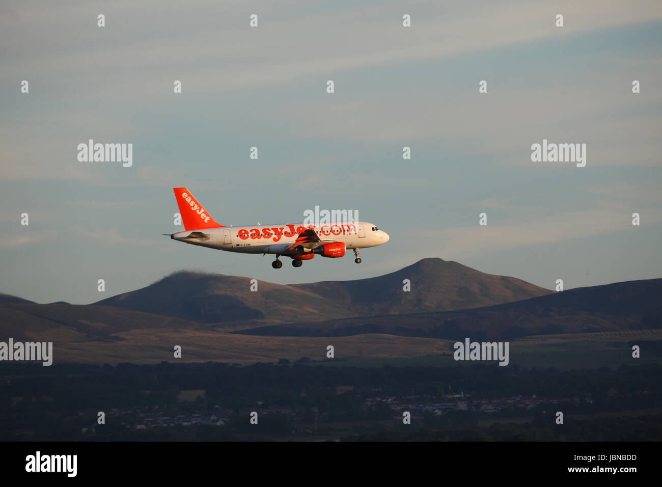 Easyjet Airbus A319-111 volo G-EZMK fa una discesa finale in aeroporto di Edimburgo con il Pentland Hills e il villaggio di Ratho in background Foto Stock