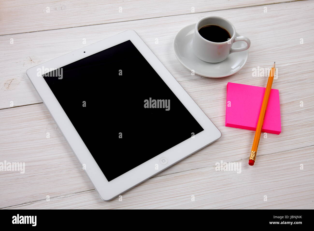 Tavoletta digitale notepad e tazza di caffè su bianco tavolo in legno Foto Stock