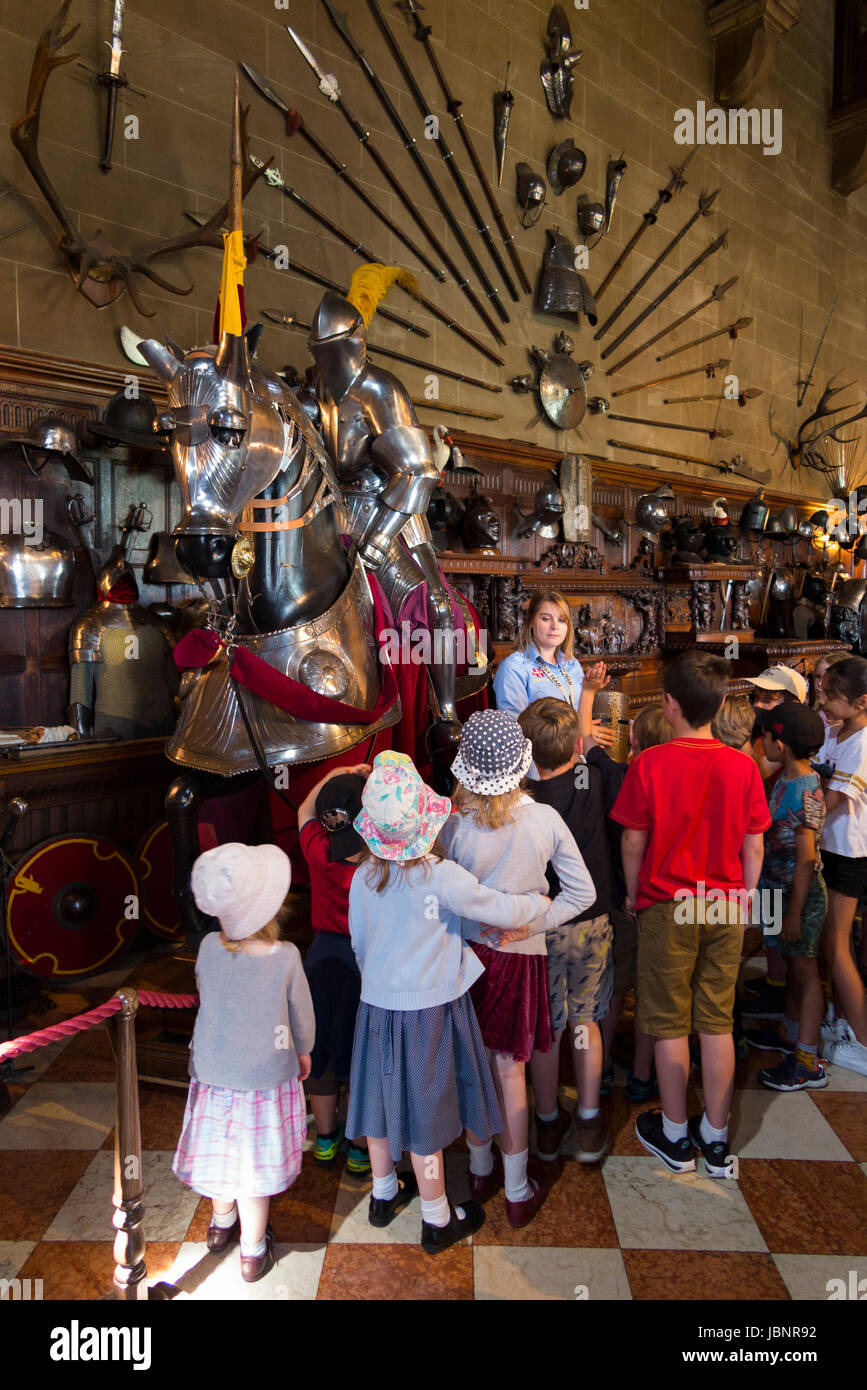 Una guida turistica parla di un display di armeria / armatura ad un gruppo di bambini e di altri visitatori nella grande hall del castello di Warwick. Warwickshire, Regno Unito. Foto Stock