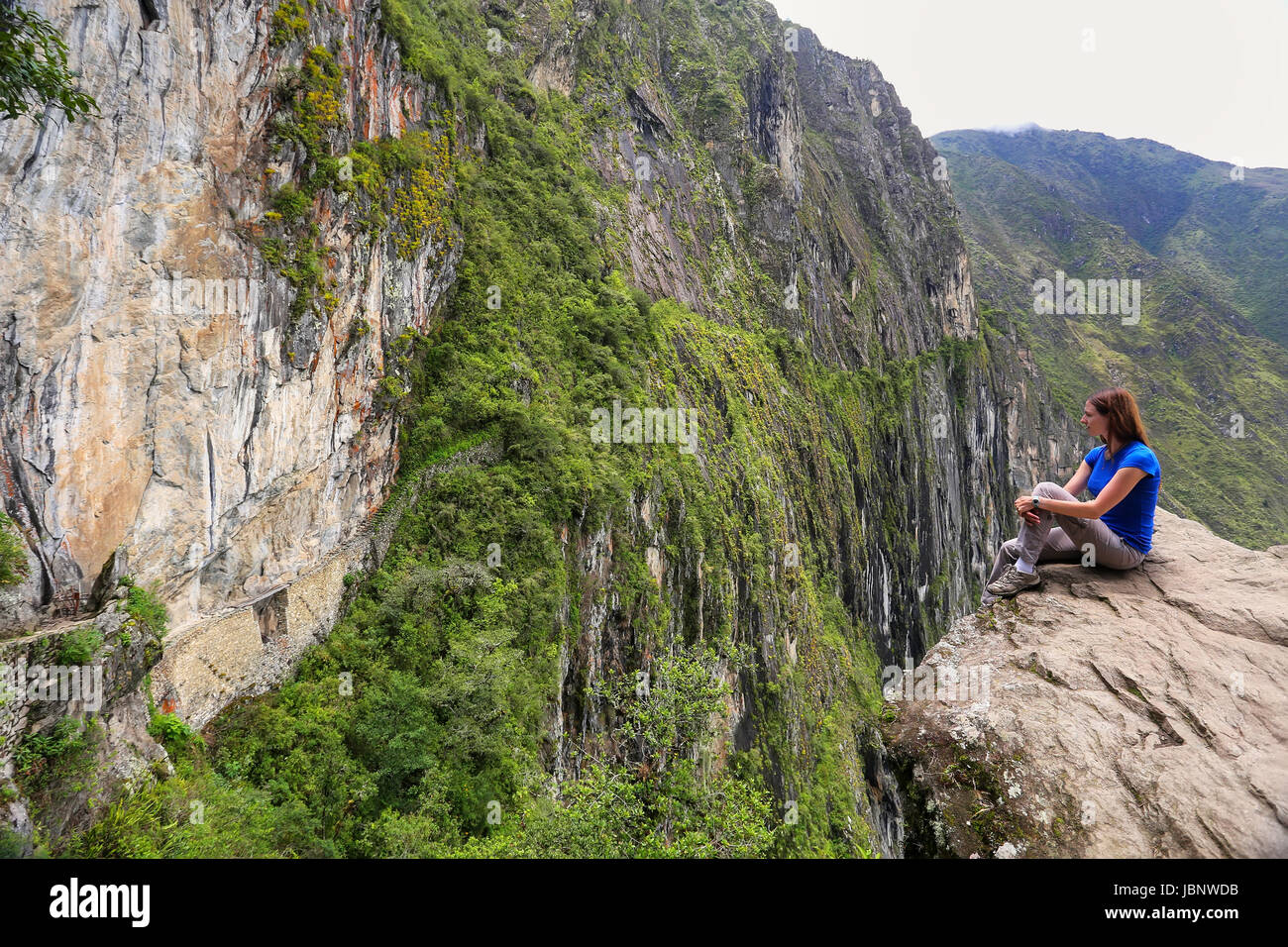 Giovane donna godendo la vista del Ponte di Inca e cliff percorso nei pressi di Machu Picchu in Perù. Il ponte è una parte di un sentiero di montagna che capi ad ovest di M Foto Stock