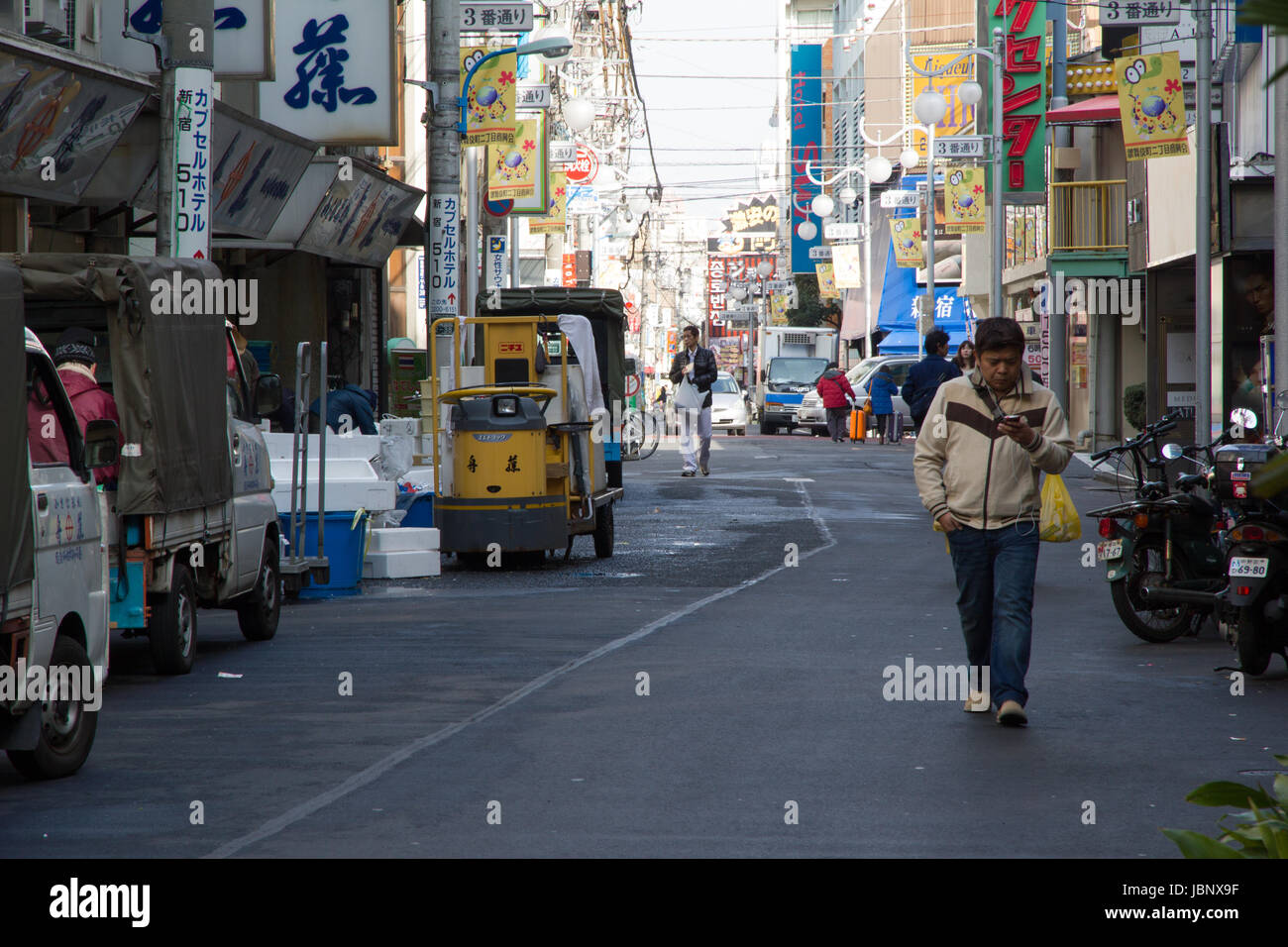 Un uomo cammina mentre distratto dal suo telefono cellulare (smombie o smartphone) zombie in una strada nella zona di Shinjuku di Tokyo, Giappone Foto Stock