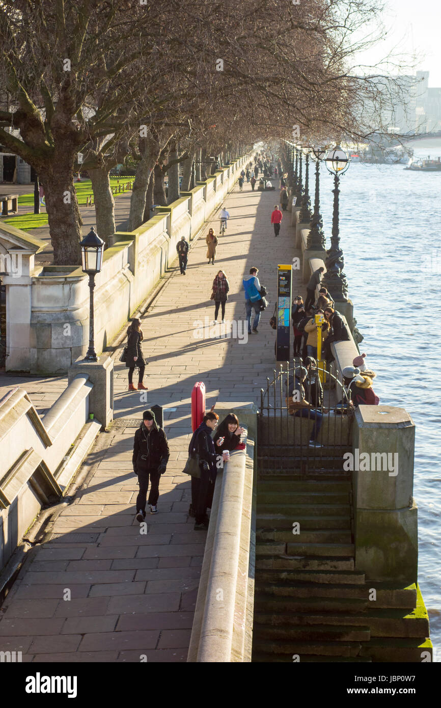 La gente camminare lungo il Tamigi percorso sulla riva sud del fiume Tamigi visto dal Westminster Bridge. Londra, Regno Unito Foto Stock