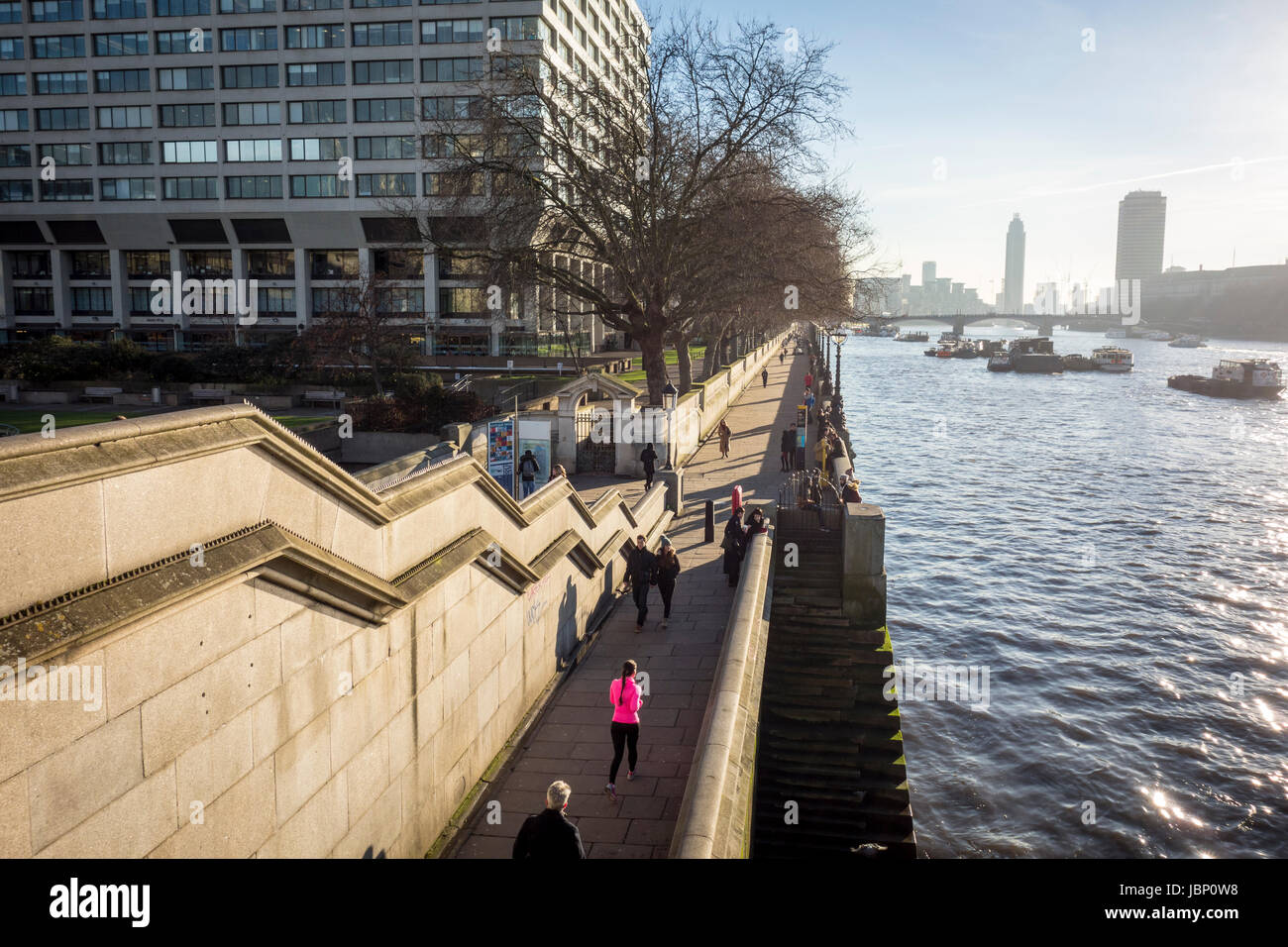 La gente camminare lungo il Tamigi percorso sulla riva sud del fiume Tamigi visto dal Westminster Bridge. Londra, Regno Unito Foto Stock
