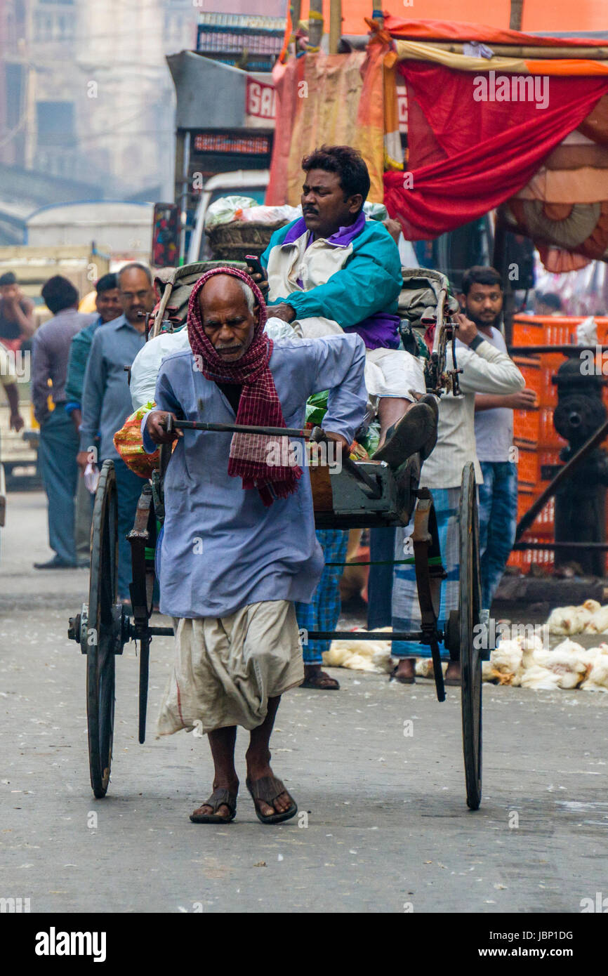 Un uomo sta tirando un rickshaw, il trasporto di un altro uomo, su una strada nel quartiere nuovo mercato Foto Stock