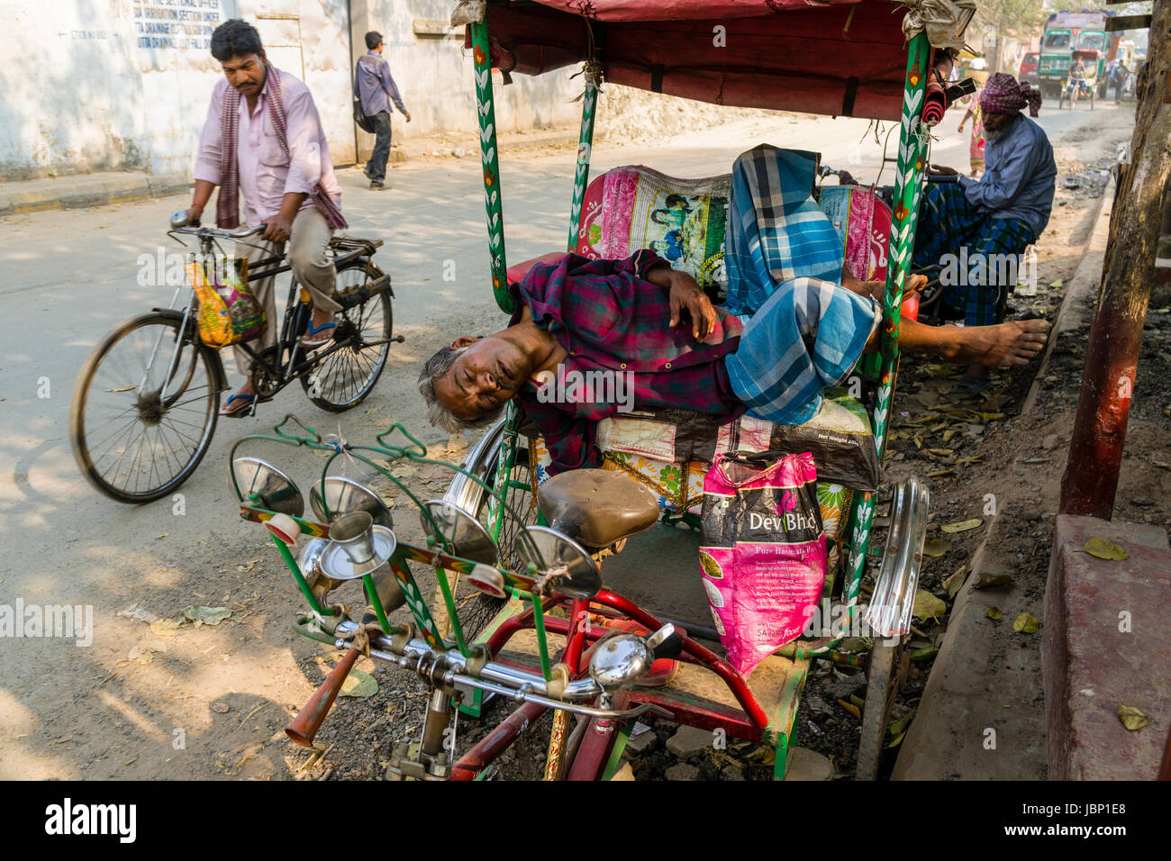 Un uomo dorme sul suo risciò ciclo su una strada nel quartiere nuovo mercato Foto Stock