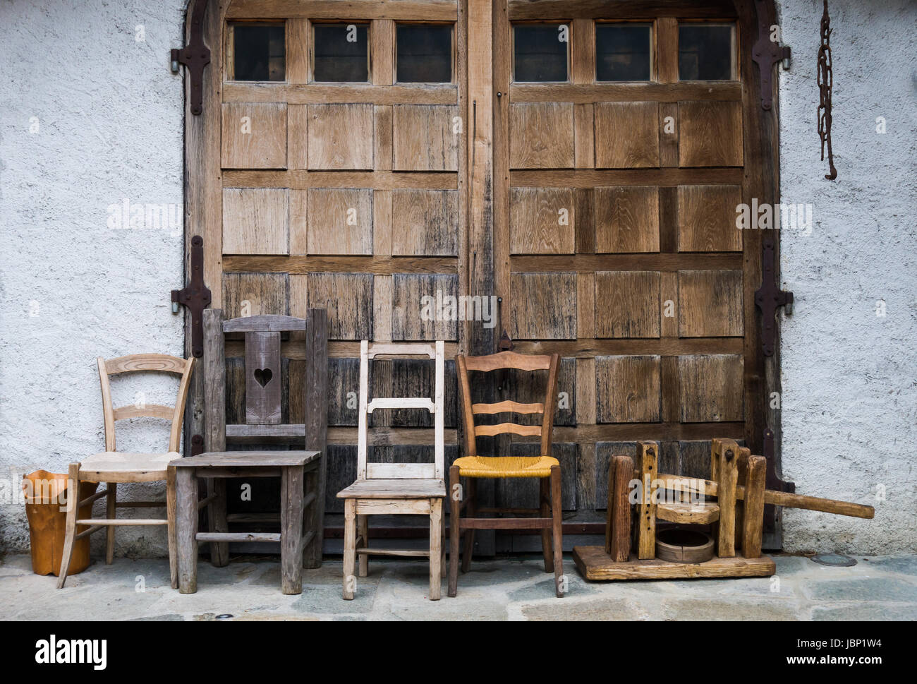 Quattro sedie e accessori fattoria schierate fuori weatherworn in legno a doppio porte del bianco-resi dependance Foto Stock