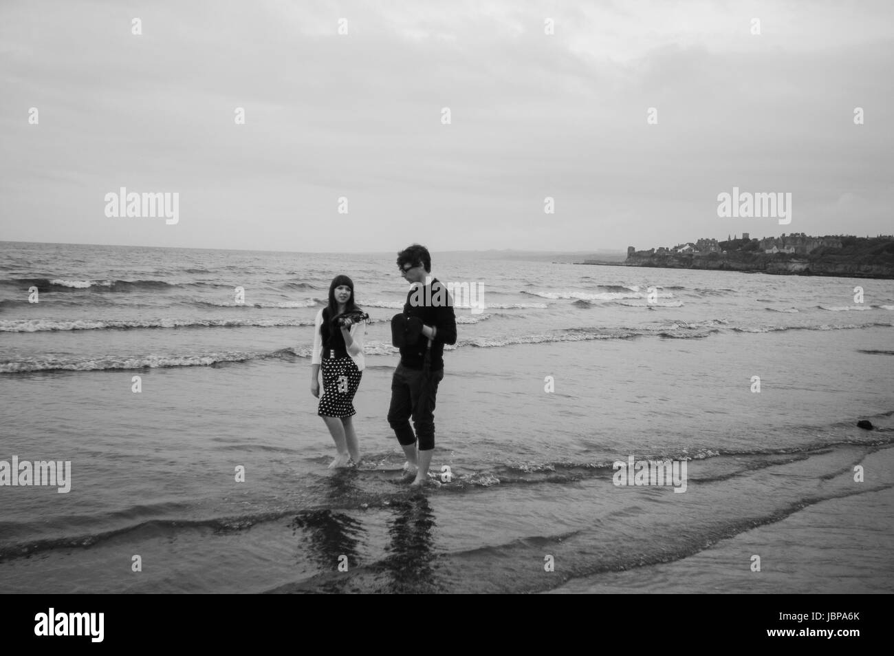 Un giovane paddling attraverso West Sands, St Andrews. La bassa marea onde sono cresta sulla spiaggia. Foto Stock