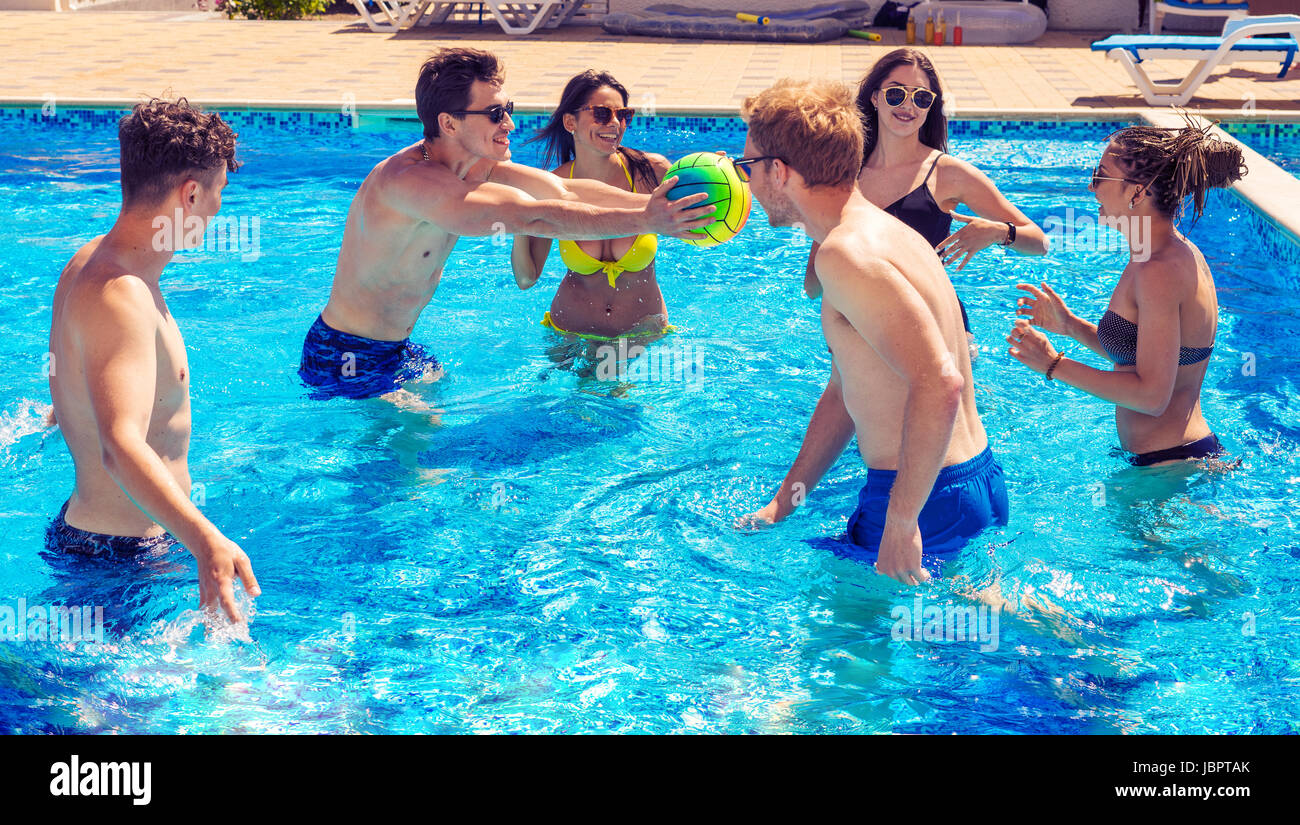 Il gruppo di allegro coppie amici giocare pallavolo in acqua Foto Stock