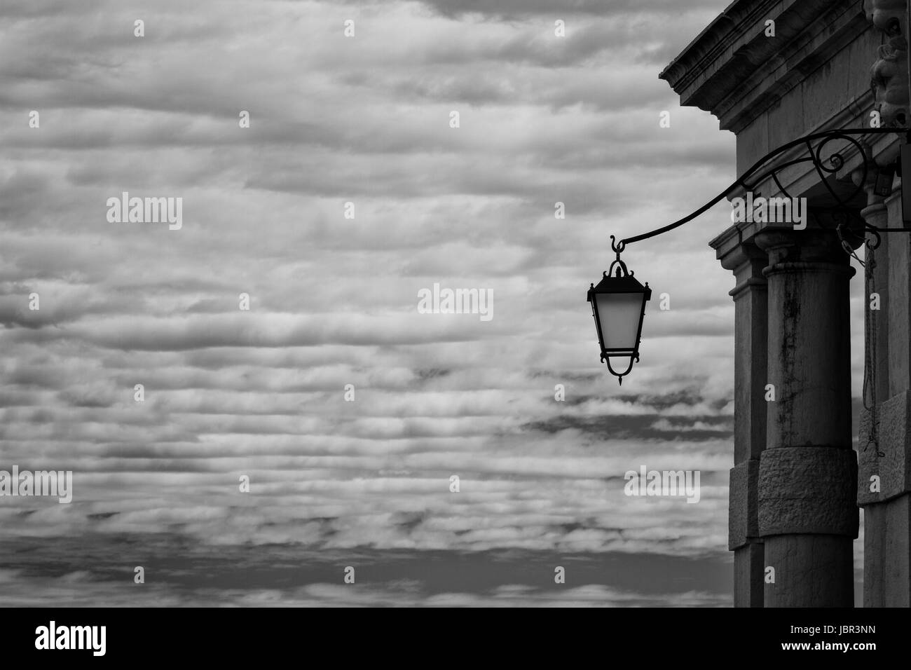 Lanterna veneziana- un singolo, ornati lanterna è protagonista come sta da solo contro la torbida estate cielo. In bianco e nero. Venezia, Italia Foto Stock