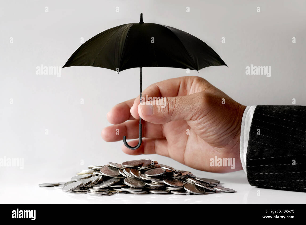Imprenditore proteggere le monete con ombrello. La sicurezza finanziaria del concetto. Foto Stock