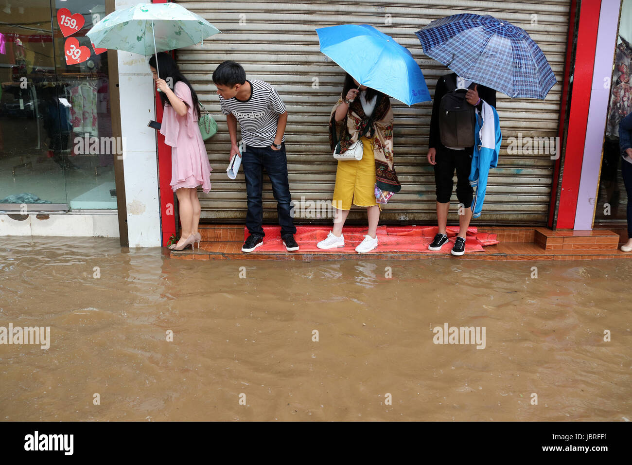 Guiyang, della Cina di Guizhou. 11 Giugno, 2017. Persone in stand by un invaso street in Weining County, a sud-ovest della Cina di Guizhou, 11 giugno 2017. Heavy Rain hit Guizhou dal Domenica. Credito: Egli Huan/Xinhua/Alamy Live News Foto Stock