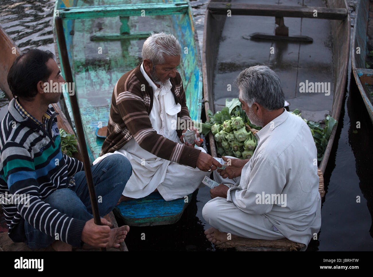 Srinagar, Indiano-controllato del Kashmir. 12 Giugno, 2017. Un uomo del Kashmir su una barca (centro) paga i soldi dopo l'acquisto da vegetali a vender al vegetale flottante sul mercato dal lago a Srinagar, la capitale estiva di Indiano-Kashmir controllata, 12 giugno 2017. La Dal lago, una delle principali attrazioni turistiche di Indiano-Kashmir controllato, è un vegetale flottante sul mercato dei materiali di consumo quali varietà di ortaggi tutto l'anno a molte parti di Indiano-Kashmir controllata. Credito: Javed Dar/Xinhua/Alamy Live News Foto Stock