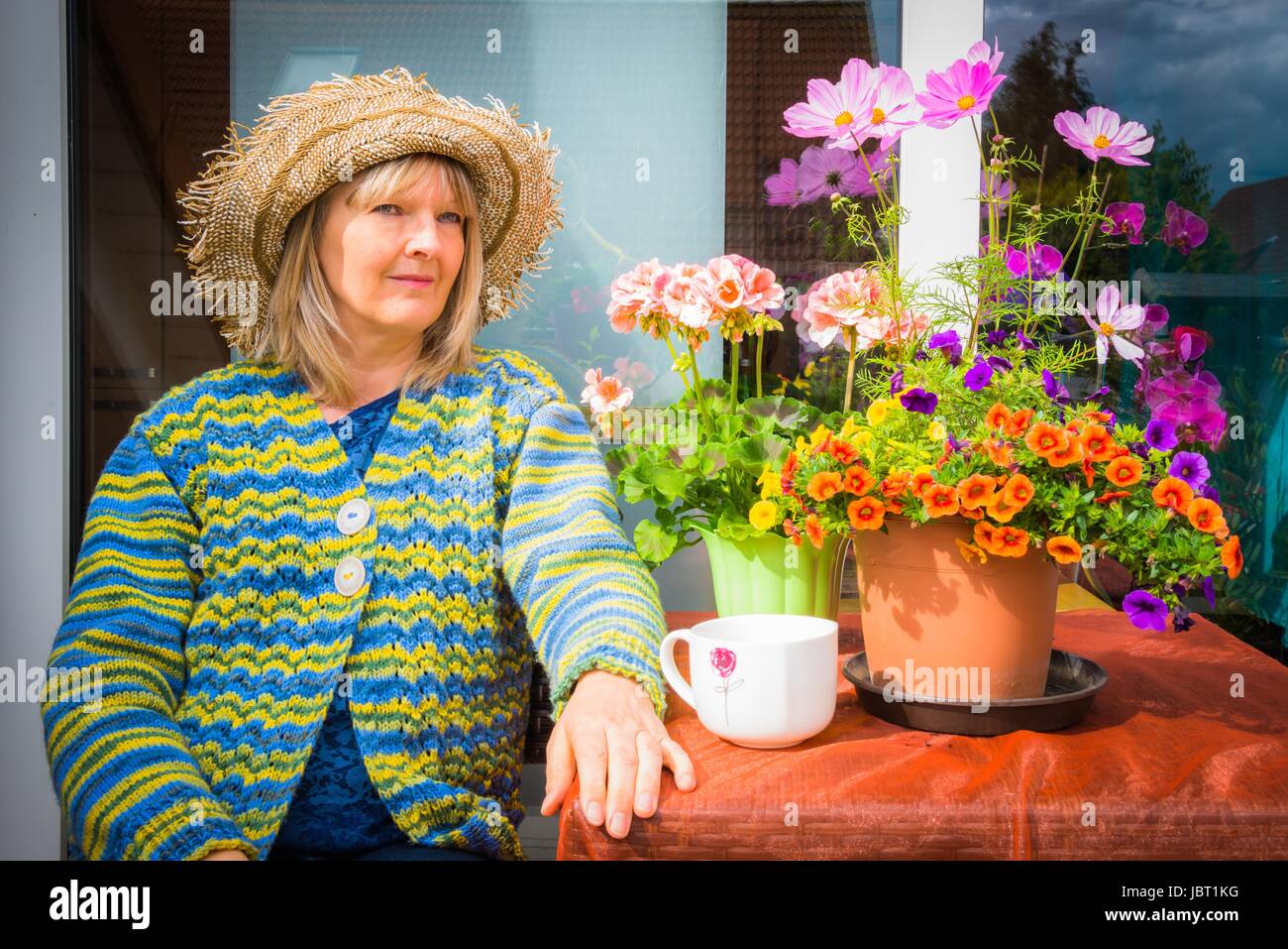 Donna seduta con fiori sul balcone Foto Stock