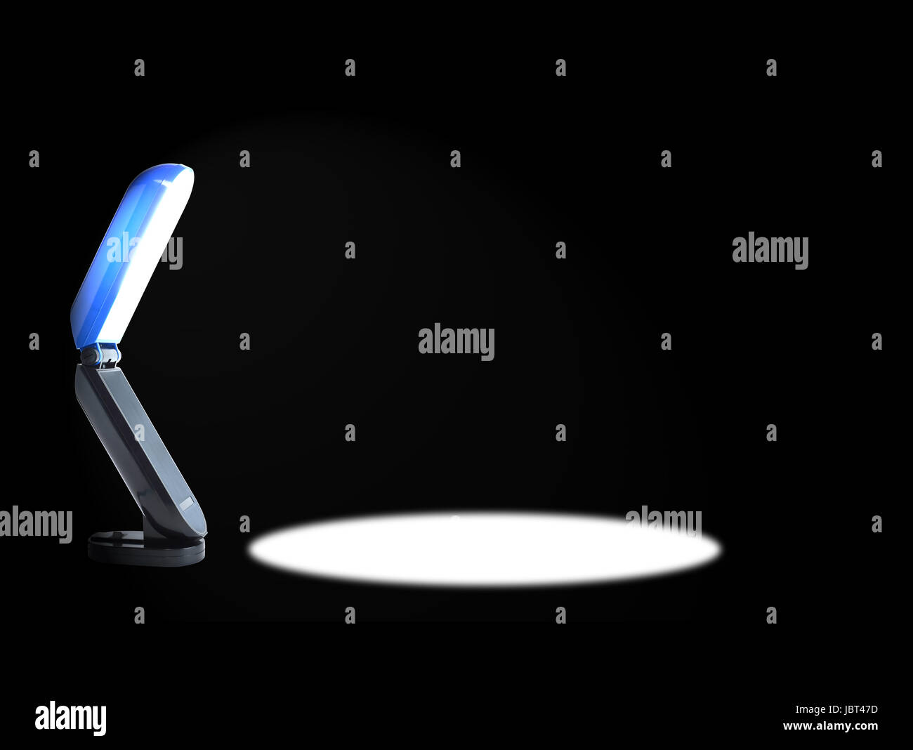 Luminoso e moderno scrivania con lampada e il fascio di luce su sfondo nero Foto Stock