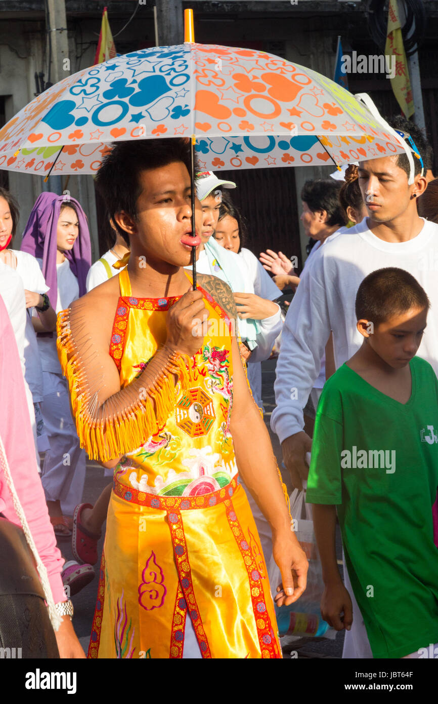 Uomo con linguetta forata da un ombrello in un corteo durante i nove imperatore dèi Festival (festival vegetariano) nella vecchia città di Phuket, Tailandia Foto Stock