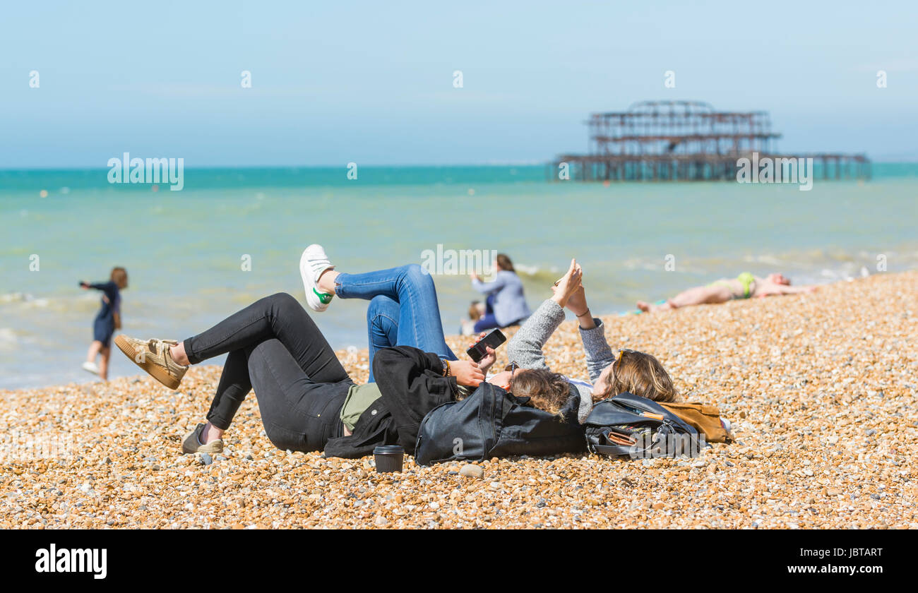 Giovani donne recante sulla spiaggia utilizzando gli smartphone. Foto Stock