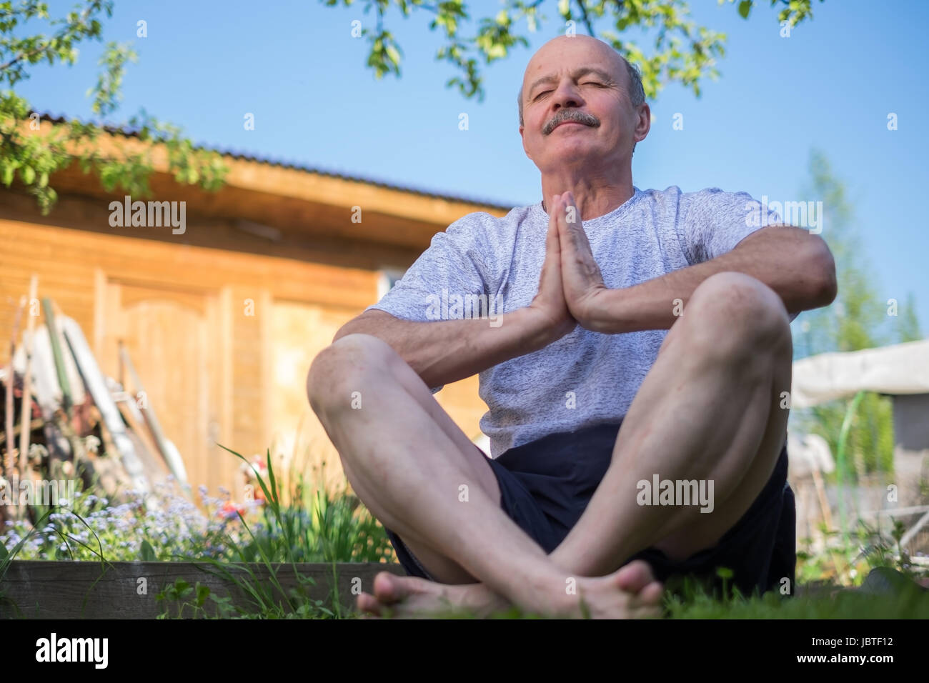 Senior uomo con i baffi con namaste seduta.Concetto di calma e di meditazione. Foto Stock