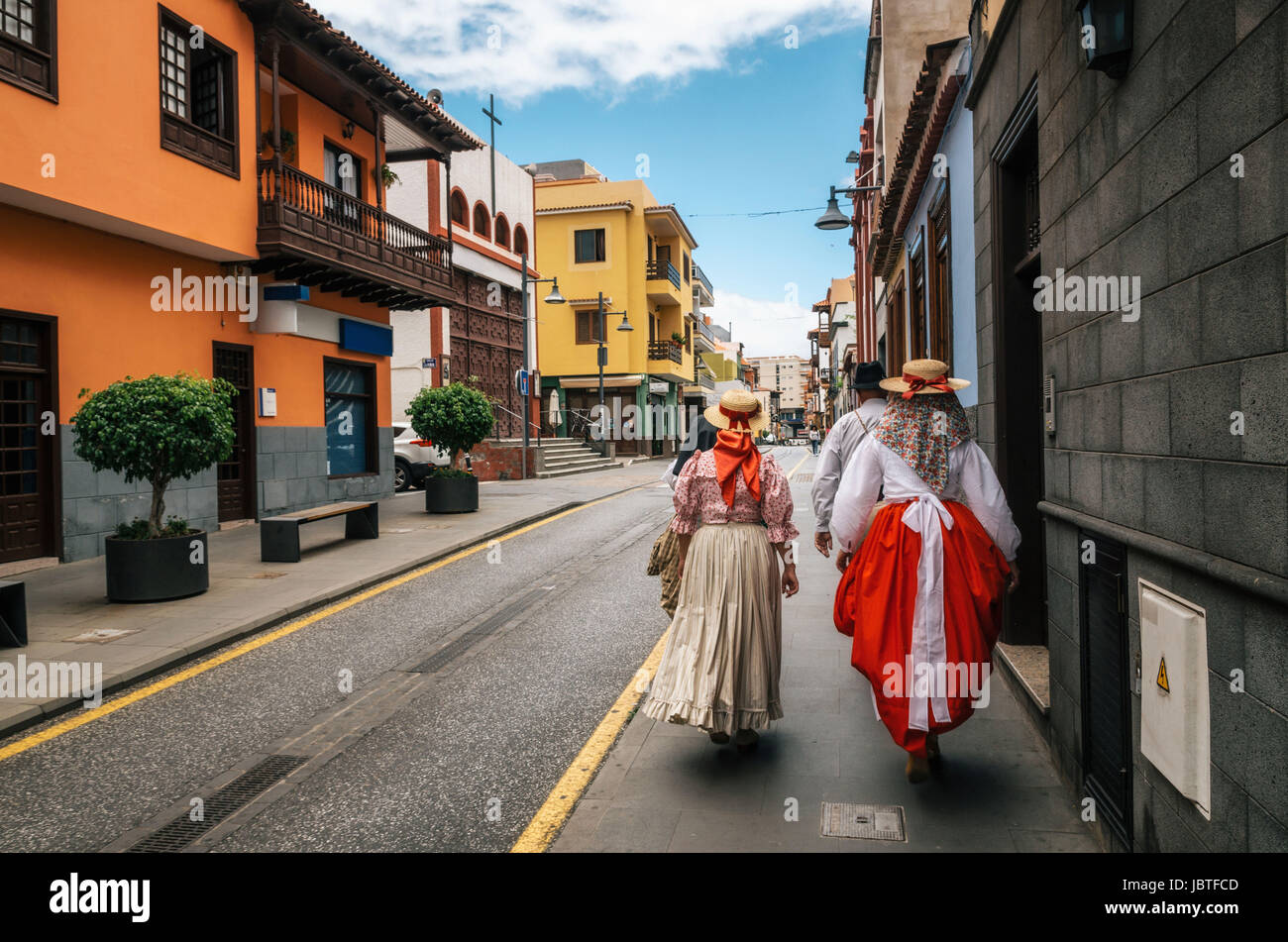 Un gruppo di abitanti locali delle Canarie abiti tradizionali a piedi lungo la strada di Puerto de la Cruz con case colorate. La celebrazione della Giornata del canarino è Foto Stock