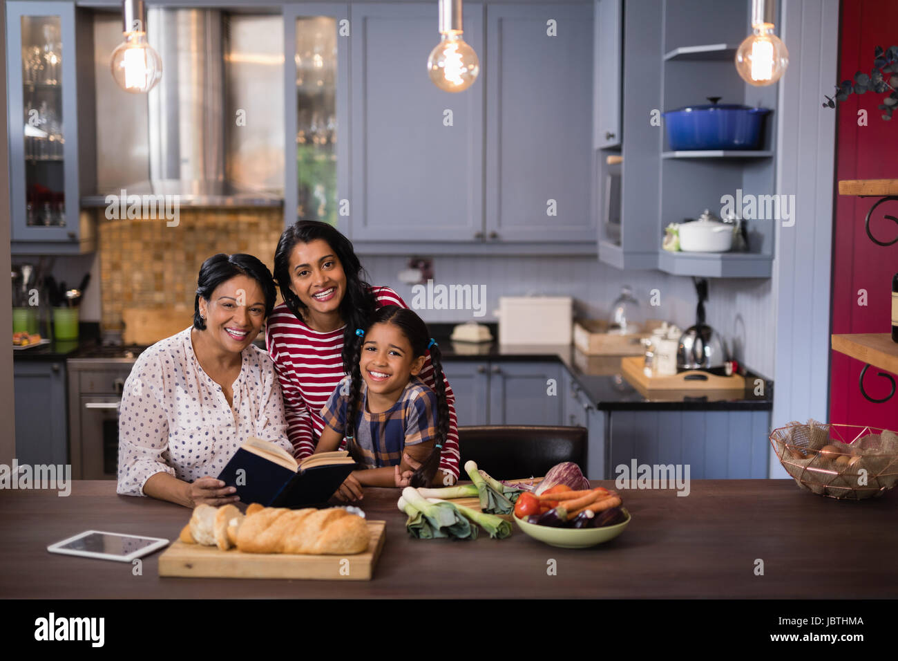 Ritratto di sorridere multi-generazione famiglia seduti insieme in cucina a casa Foto Stock