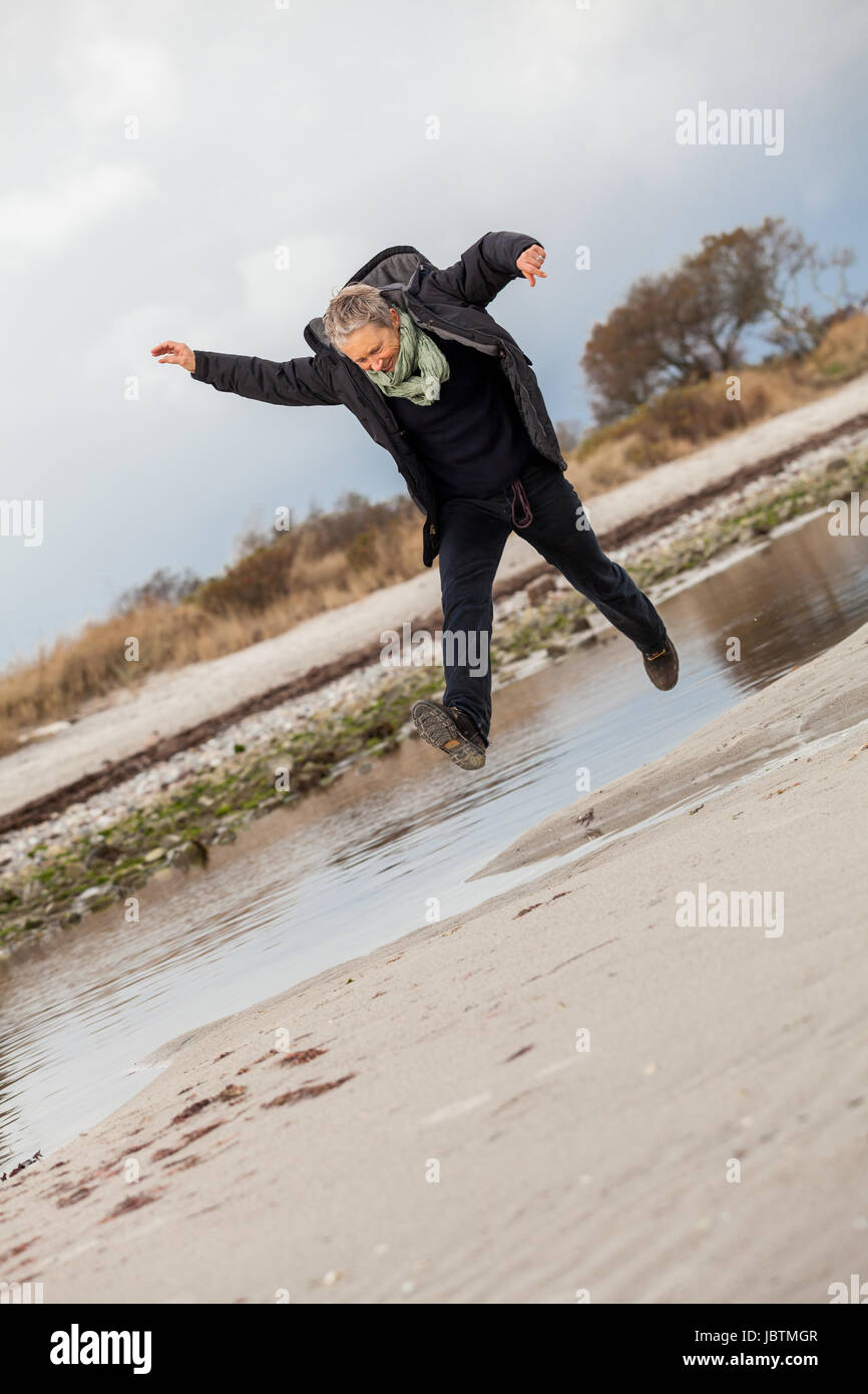 Glückliche aktive ältere frau rentnerin seniorin im freien am Meer im herbst Foto Stock