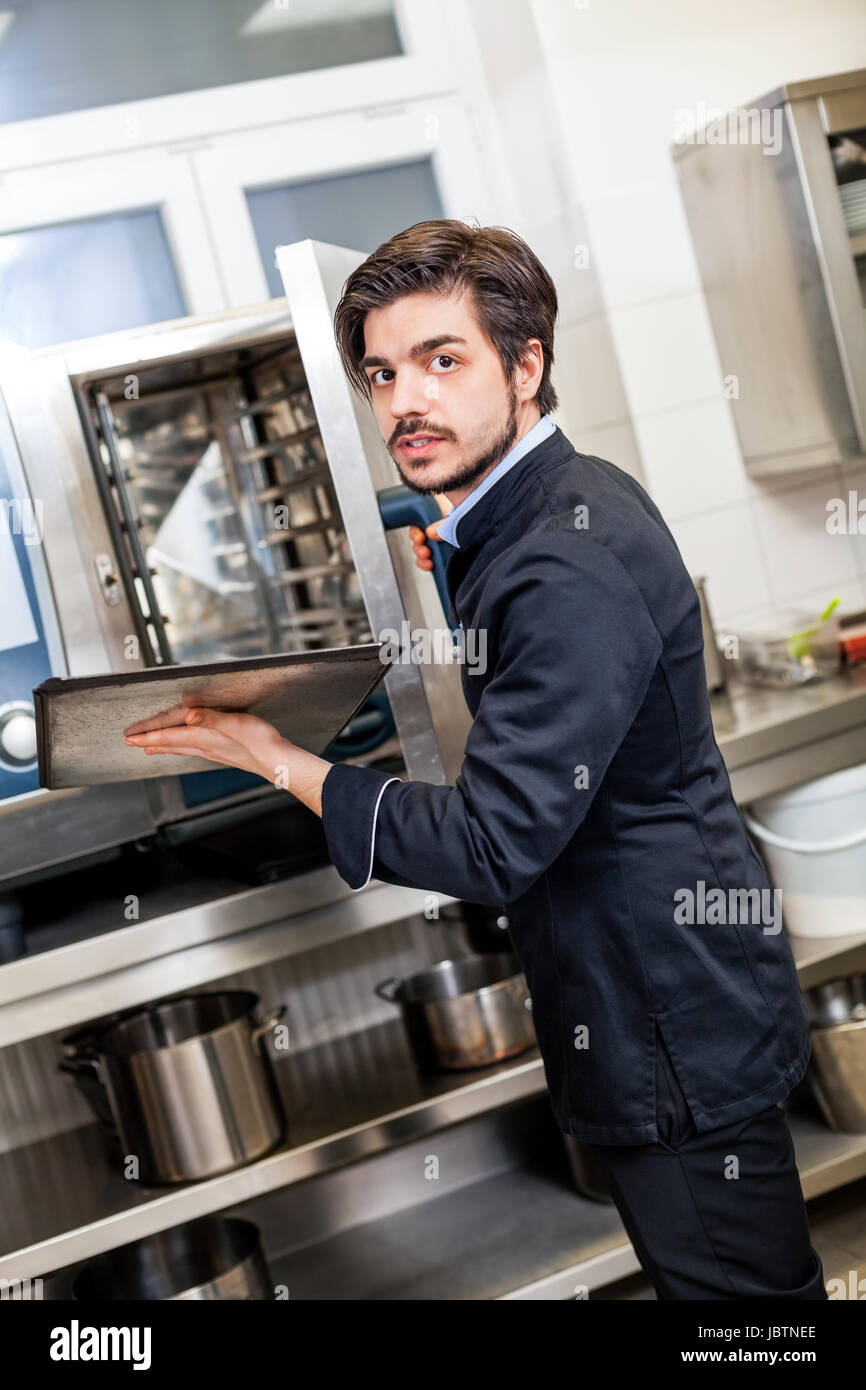 Junger erwachsener chefkoch in der ristorante küche beim kochen am zubereitung mandria Foto Stock