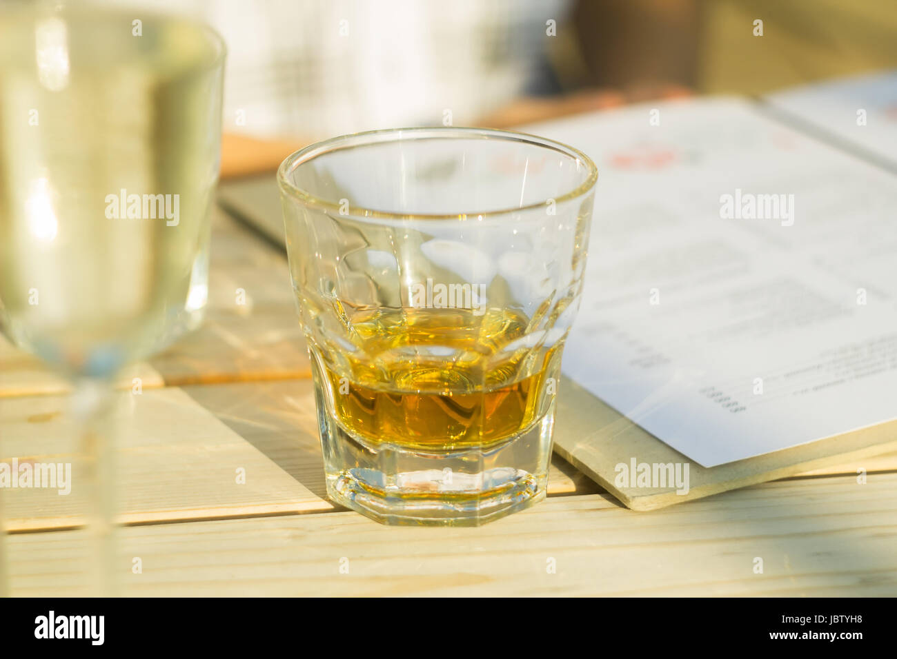 Un bicchiere di whisky accanto a un menu aperto presso un ristorante Foto Stock