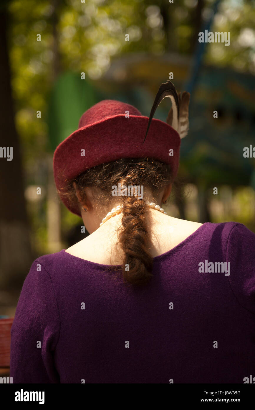 Giovane donna caucasica indossando costume storico - di feltro abito viola  e rosso Tirol con cappello di piume. Bella Signora vista posteriore alla  rievocazione medievale Foto stock - Alamy