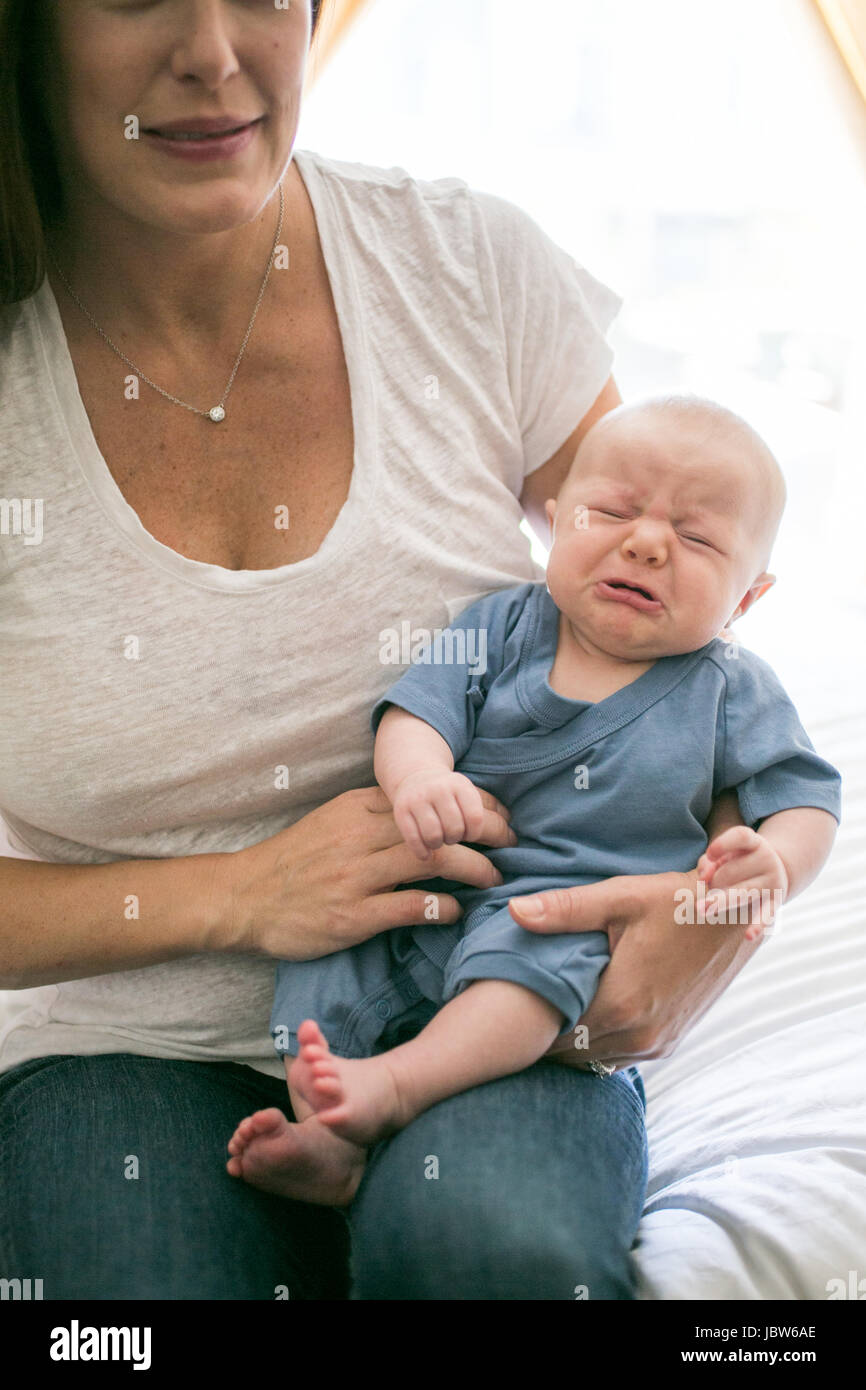 Madre seduta con il pianto baby boy Foto Stock