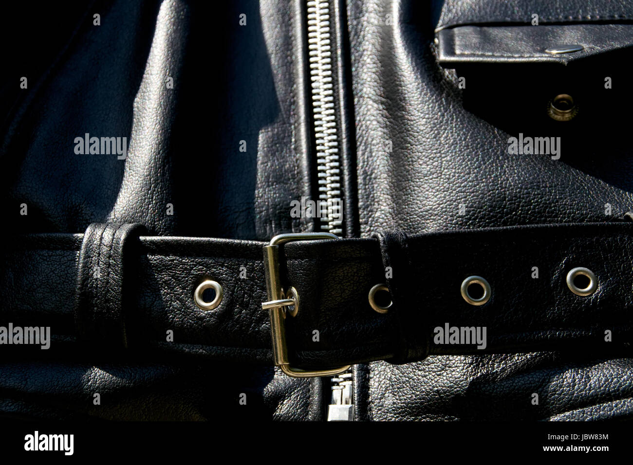 Close up di pelle nera giacca biker che mostra la cinghia e la cerniera e taschino nella luce del sole. Foto Stock