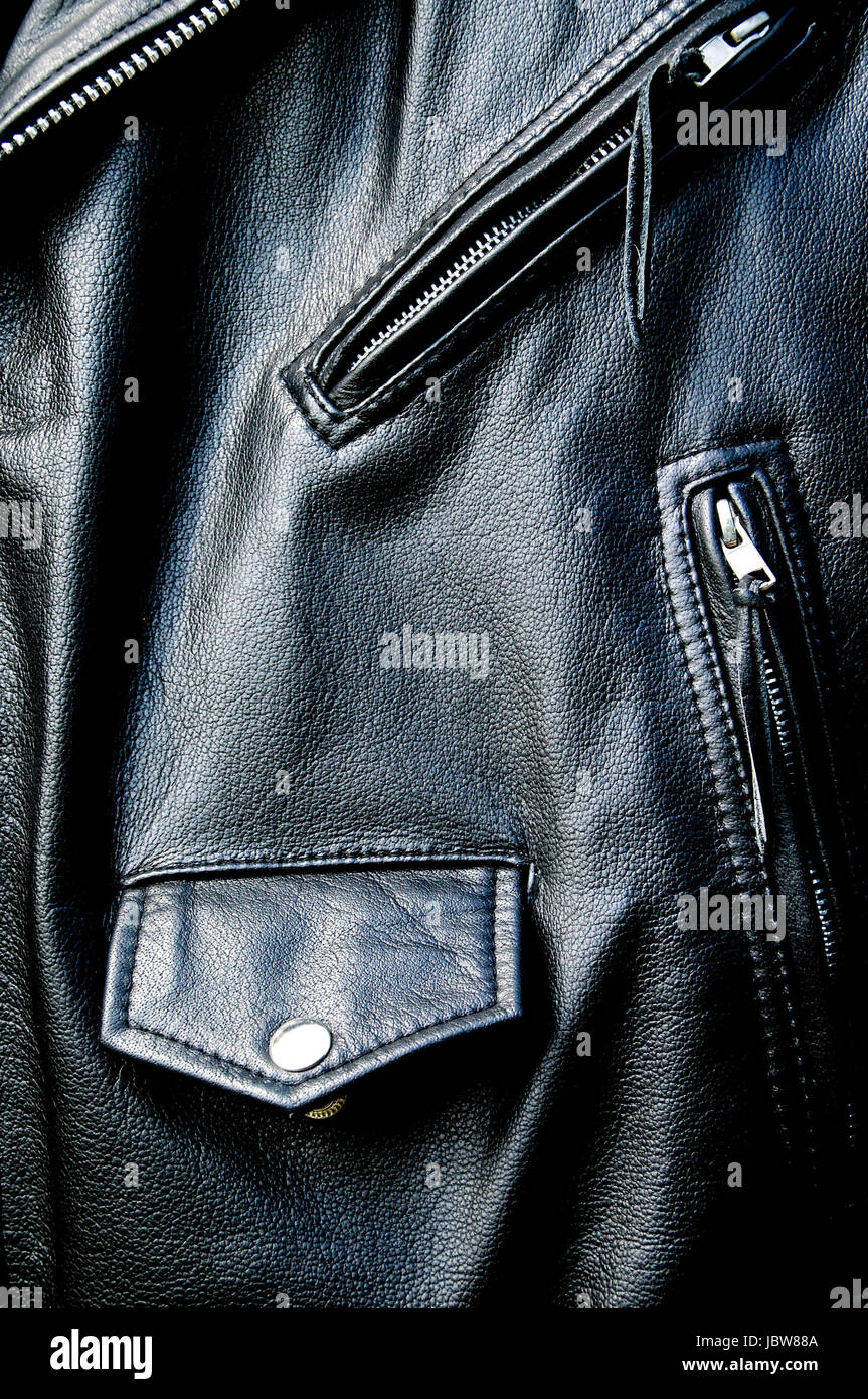 Alto contrasto close up di pelle nera giacca biker mostrando tasche con cerniera e taschino con pulsante di scatto e il tratto di cinghia a sunshine. Foto Stock