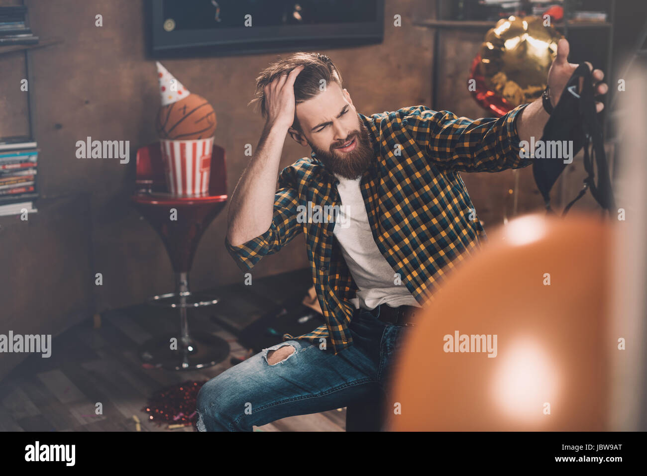 Barbuto giovane con mal di testa tenendo reggiseno nero dopo essere partito Foto Stock
