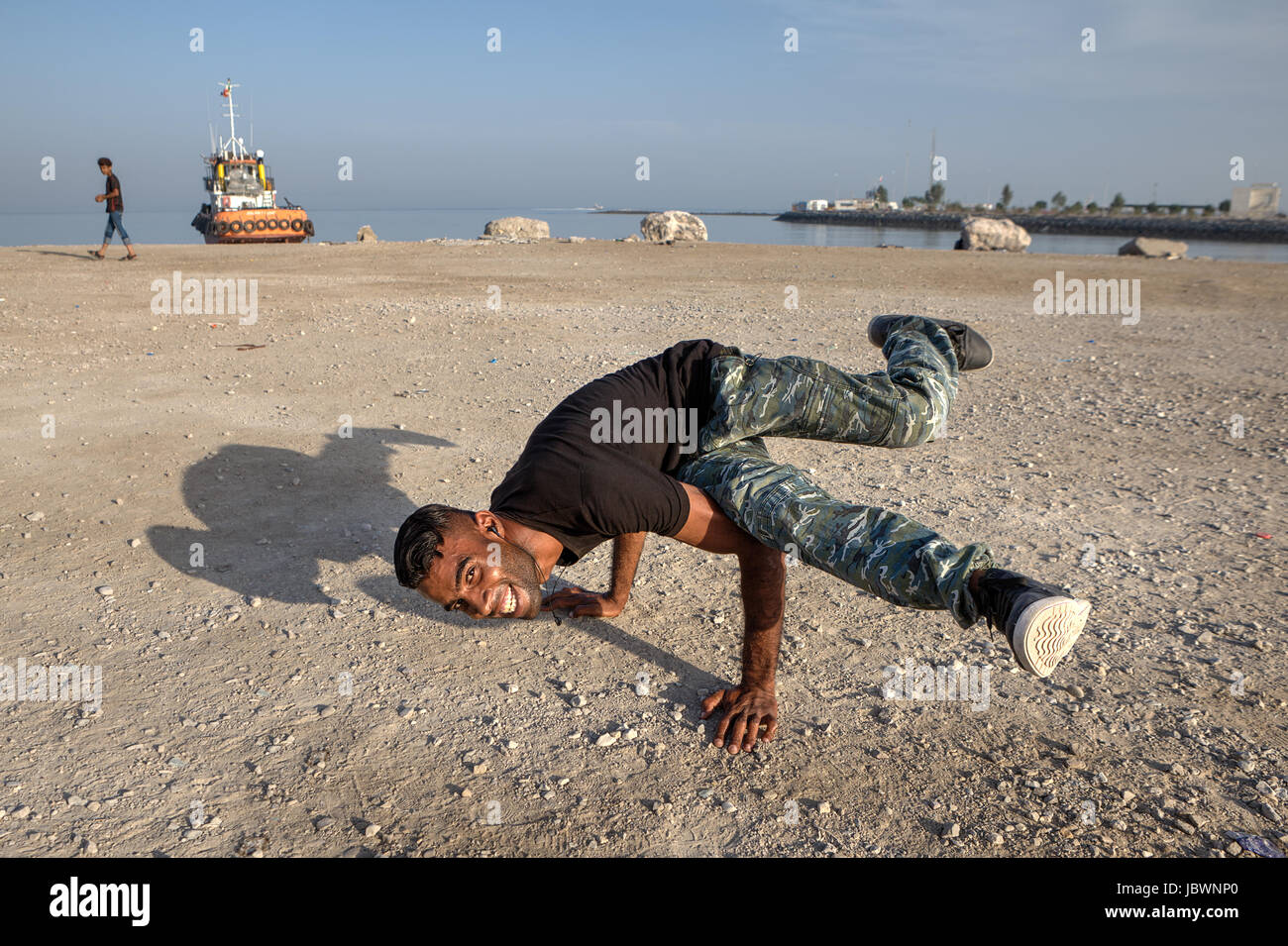 Bandar Abbas, Hormozgan Provincia, Iran - 16 aprile, 2017: gioventù araba mostra la figura, break dance sulla spiaggia del golfo Persico. Foto Stock