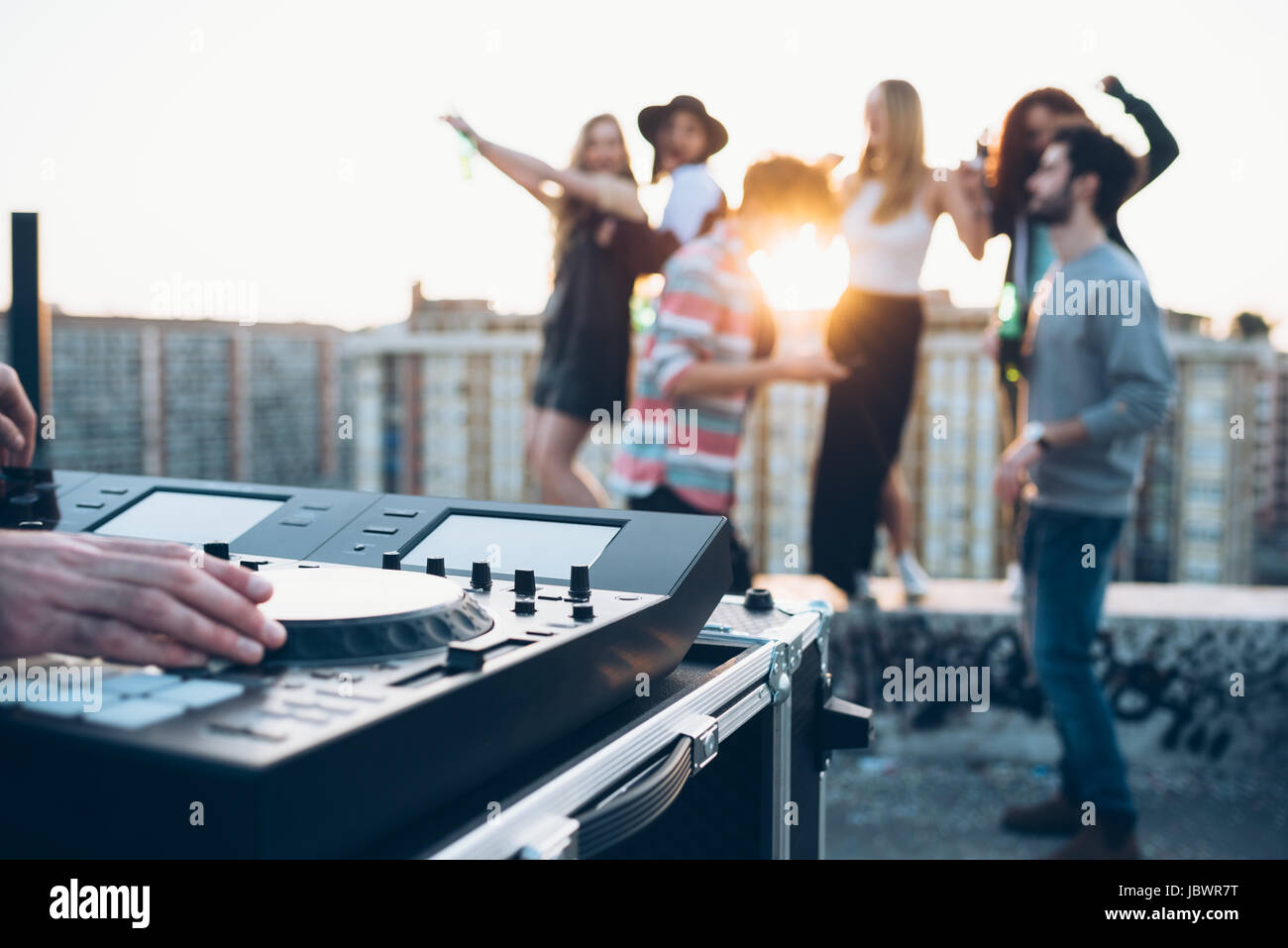Gruppo di amici godendo di parte del tetto, giovane uomo utilizzando console di mixaggio Foto Stock