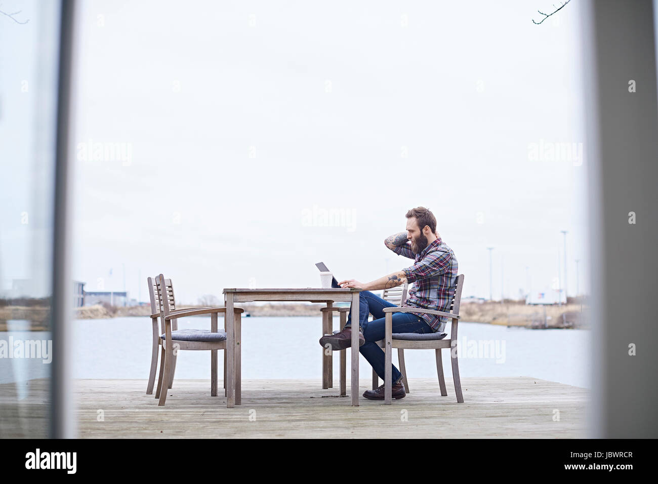 Giovani designer maschio utilizzando digitale compressa sul lungomare al di fuori dell design studio Foto Stock